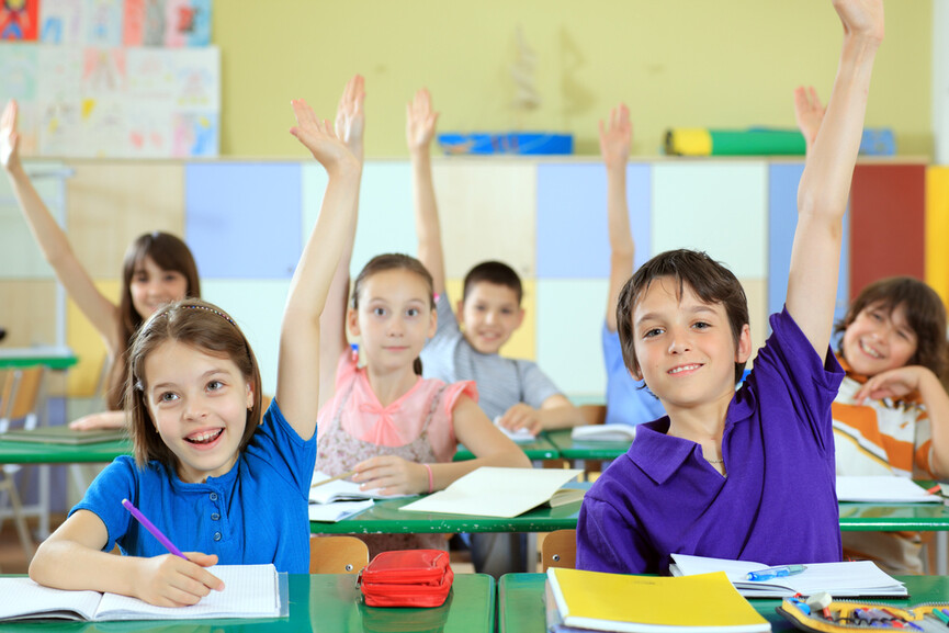 Students in a classroom raising their hands